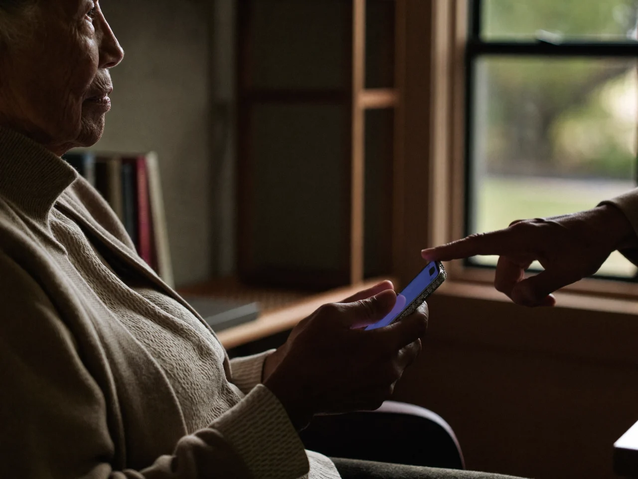 Vejlederens hånd peger roligt, mens en kvinde holder sin smartphone